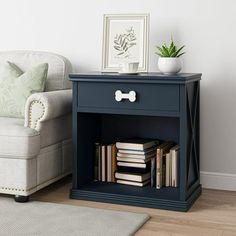 a blue nightstand with books on it next to a white chair and potted plant