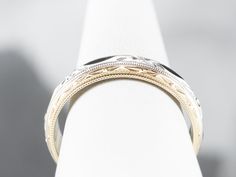 This vintage band is crafted entirely of 14k gold, with yellow gold framing the edge of the ring, and white gold creating a floral accented center. The center of this ring is slightly domed, giving it the ability to catch the light and accented by the waving, faceted edge. Metal: 14K Yellow and White Gold Width of Band: 6.5 mm Height off Finger: 2.1 mm Ring Size: 12.25 Marks: "14KT" Stamped on the inside band Timeless Yellow Gold Engraved Ring With Decorative Band, Luxury White Gold Open Band, Heirloom Rings With Decorative Band, Fine Jewelry Wedding Rings With Milgrain Detail, Classic White Gold Engraved Ring With Open Band, Classic Diamond Ring With Decorative Band For Formal Events, Classic Formal Diamond Ring With Decorative Band, Timeless Yellow Gold Wedding Ring With Intricate Design, Elegant Yellow Gold Engraved Band