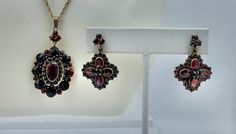 This is a gorgeous Victorian Bohemian Garnet Parure with a stunning Pendant and pair of Earrings. The garnets sparkle with a brilliant red fire, they are of a wonderful size and the design is absolutely gorgeous. All of the garnets are matched and original to the jewels. The garnets are all set "a jour" - open backed, in order to let the maximum amount of light through. The pendant has a central oval faceted garnet of great beauty. It is surrounded by two further halos of garnets and has a trefoil garnet set bale. The earrings have quatrefoil design with four flower rondelles in each earring. The garnets are set in silver gilt which is referred to as "Garnet Gold" and was the custom of the period. These magnificent Bohemian Garnet jewels date to the Victorian period, circa 1880. The pendan Victorian Period, Garnet And Gold, Garnet Pendant, Red Fire, Necklace And Earrings, Vintage Watches, Antique Jewelry, Jewelry Sets, Vintage Antiques