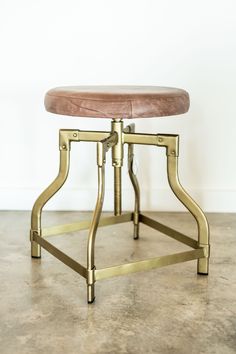 a small stool with a wooden seat and metal frame on the bottom, against a white wall