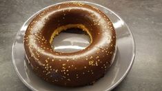 a chocolate donut with gold sprinkles on a white and silver plate