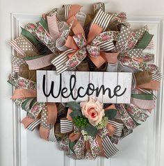 a welcome sign is hanging on the front door with flowers and ribbons attached to it