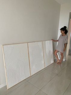 a woman standing next to a white wall with three panels on it and one panel missing