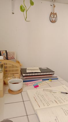 a desk with books, notebooks and a cup of coffee on top of it