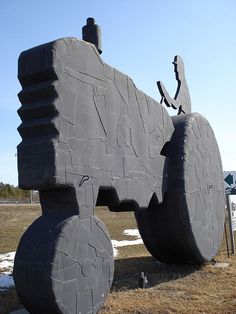 a large gray sculpture sitting on top of a grass covered field