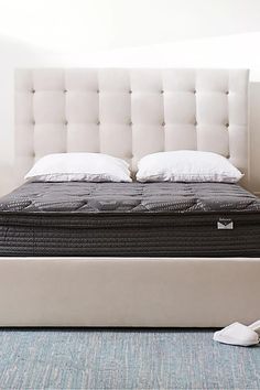 a bed with a white headboard sitting on top of a blue carpeted floor