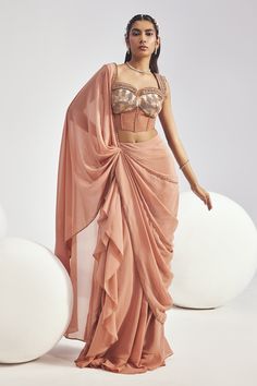 Blush pink concept saree with embroidered border. Paired with a padded corset blouse with mesh detailing, cutdana, sequins embroidery. Components: 2 Pattern: Embroidery Type Of Work: Sequins, Cutdana Neckline: Sweetheart Neck Sleeve Type: Sleeveless Fabric: Corset: Satin and Tulle, Saree: Georgette Color: Pink Other Details:  Attached lining Blouse Padded Sequins embroidered straps Saree: Mild ruffle detailing Occasion: Reception - Aza Fashions Luxury One-shoulder Designer Saree, Luxury Designer Saree With Cutdana, Luxury Saree With Cutdana And Cape Sleeves, Luxury Lehenga Saree With Padded Blouse, Luxury Pink Pre-draped Saree With Intricate Embroidery, Luxury Saree With Padded Blouse, One Shoulder Saree Blouses, Luxury Pink Saree With Tilla Detailing, Corset Blouse With Sleeves