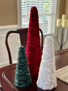 three knitted trees sitting on top of a wooden table