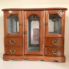 a wooden cabinet with glass doors and drawers