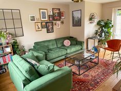 a living room with green couches and pictures on the wall