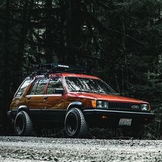 an orange and black car parked in the woods