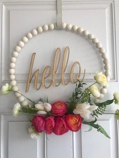 a wreath with flowers and the word hello hanging on it's front door frame