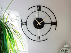 a black and white clock on the wall next to a potted plant