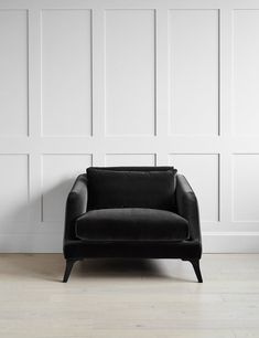 a black chair sitting in front of a wall with white paneling on the walls