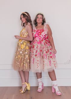 two women standing next to each other in dresses and high heeled shoes with flowers on them