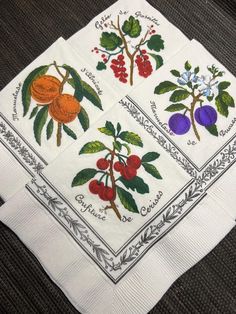 three white napkins with fruit on them