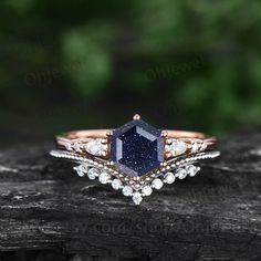 a blue and white diamond ring on top of a piece of wood with trees in the background