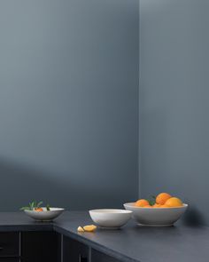 two bowls with oranges sit on a counter