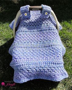 a blue crocheted bag sitting on top of the grass next to a tree