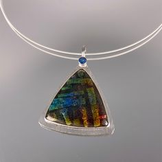 This one-of-a-kind pendant features kiln-fired vitreous enamel over multiple layers of silver and 24K gold foils. The sterling and fine silver closed-back setting has a 5MM faceted blue topaz, a chiseled edge, and subtle texture. The bale will accommodate a thick chain or neckwire. Pendant comes with a 2.4mm coiled sterling silver neckwire with tension closure. Pendant is 2.18"wide *please use my contact form to request additional information or photos Blue Fusion Jewelry With Large Pendant, Multicolor High Luster Necklace For Gift, Multicolor High Luster Necklaces As Gift, Contemporary Blue Jewelry For Gifts, Unique Silver Jewelry With High Luster, Unique High Luster Silver Jewelry, Blue Cabochon Fusion Jewelry, Modern High Luster Jewelry As Gift, Modern High Luster Jewelry For Gift