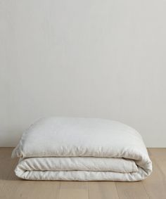 two white pillows stacked on top of each other in the middle of a wooden floor