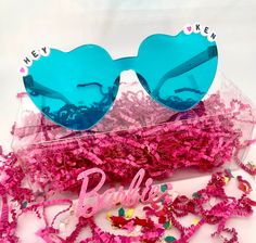 pink and blue sunglasses sitting on top of a plastic container filled with confetti