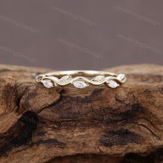 a gold wedding band with three diamonds on top of a piece of drift wood,