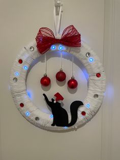 a christmas wreath with ornaments hanging from it's side and a cat on the front