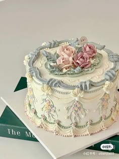 there is a white cake with pink flowers on the top and blue trimmings