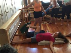 a woman laying on the floor in front of other women doing yoga exercises with each other