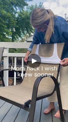 a woman standing on top of a wooden deck next to a chair with a back cushion