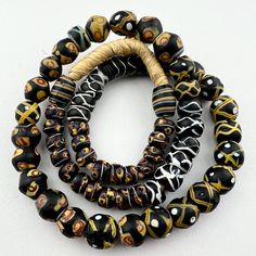 three bracelets with black and gold designs on them