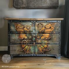 an old dresser has been painted with butterflies and gears on the front, as well as metal