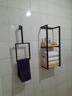 two black shelves with towels on them in a white tiled bathroom, next to a shower