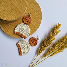 two crocheted earrings are next to some dried flowers