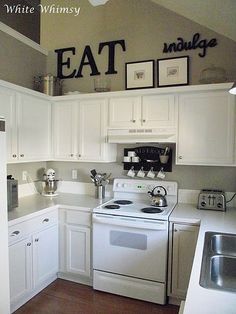 a kitchen with white cabinets and an eat sign on the wall above the stove top