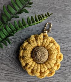 a crocheted keychain with a yellow flower on it and a green leaf