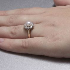 Belle Epoque Pearl and diamond ring. The center pearl of this ring has a slight rosy hue and is surroundeed by a border of eleven Old Mine Cut diamonds (total diamond weight apx 0.50 cts, H-K color and VS-SI clarity). The pearl is 6.25 mm in diameter and the ring is a size 5. Resizing may be possible, please inquire. A vintage original. Two-tone 14k gold. Formal Diamond Halo Pearl Ring, Formal Diamond Pearl Ring With Halo, Formal Pearl Ring With Diamond Halo Design, Formal Diamond Pearl Ring With Halo Design, Classic Pearl Ring With Diamond Halo Setting, Elegant Cluster Halo Ring, Elegant Cluster Pearl Ring For Formal Occasions, Elegant Formal Cluster Pearl Ring, Classic White Pearl Ring With Rose Cut Diamonds