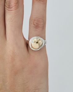 a person's hand with a ring on it that has a heart in the middle