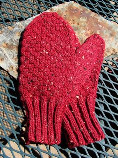 a red mitten sitting on top of a grill grate next to a stone