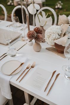 a table set with place settings, silverware and flowers in vases on it