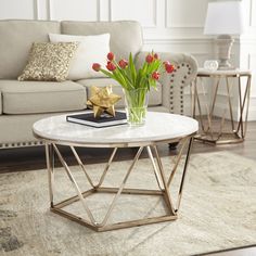 a living room with a couch, coffee table and flowers in a vase on top