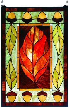 a stained glass window with an orange leaf in the center and leaves on it's sides