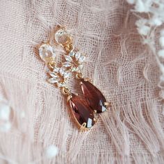 a close up of a piece of jewelry on a lace table cloth with beads and stones