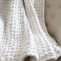 a white crocheted blanket sitting on top of a chair