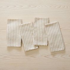 three white and beige striped towels laying on top of a wooden table