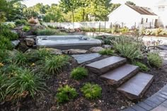 a hot tub sitting in the middle of a garden next to a stone walkway and steps