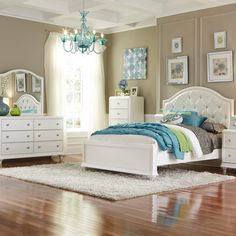 a white bed sitting on top of a wooden floor next to a dresser and mirror