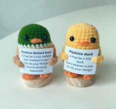 two crocheted stuffed animals holding signs with words written on them that say positive and negative