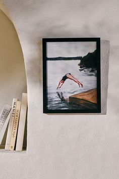 a book shelf with books on top of it and a photo hanging from the wall